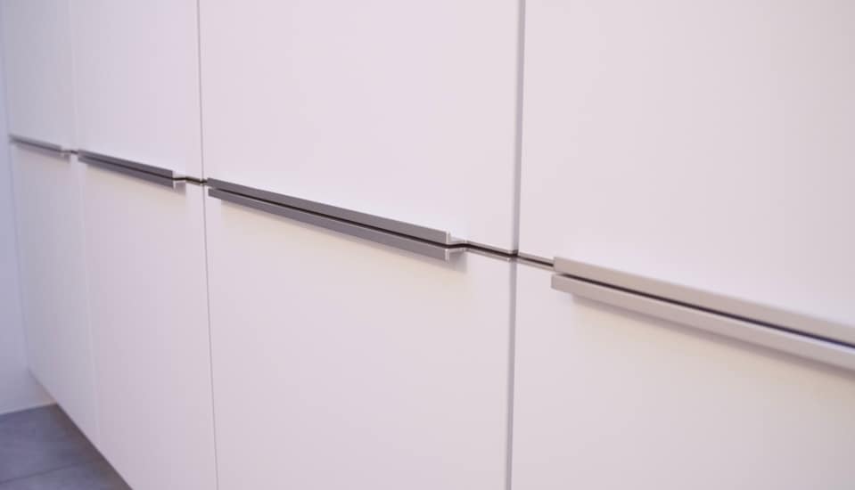 Portes de placard blanches avec poignées métalliques horizontales dans une cuisine moderne.